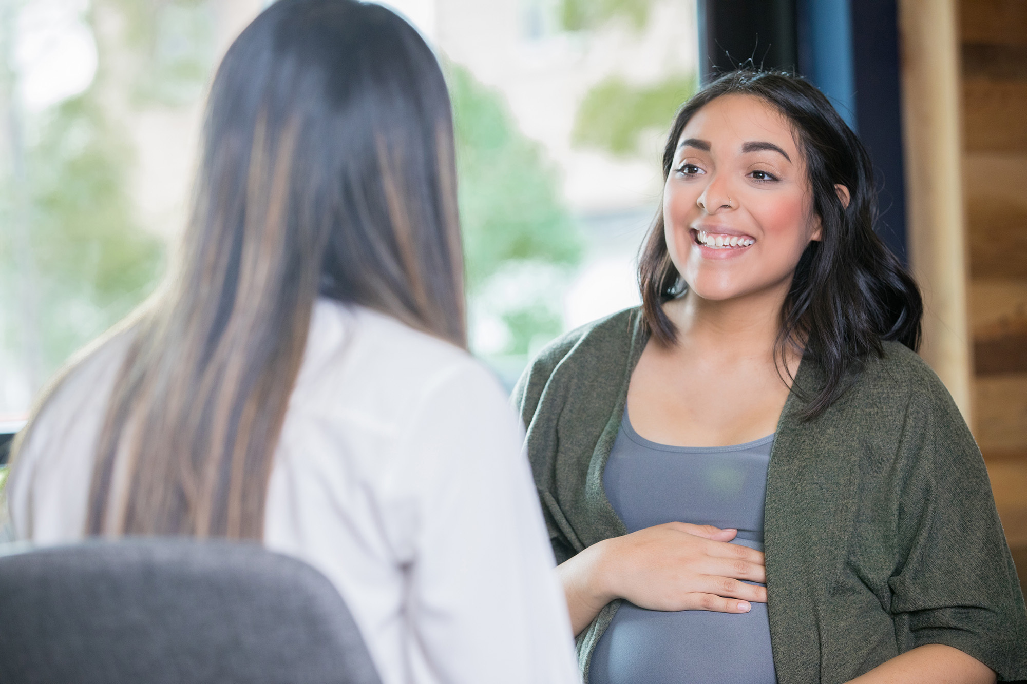 Young adult Hispanic expectant mother is discussing her pregnancy with a midwife during a support group meeting or childbirth class.