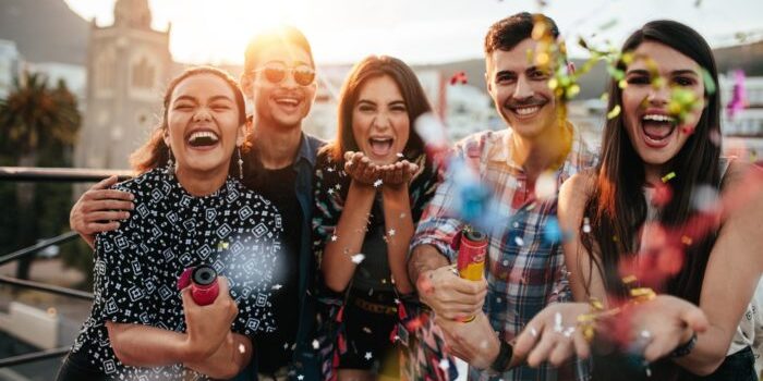 Group of friends enjoying party and throwing confetti. Friends having fun at rooftop party.