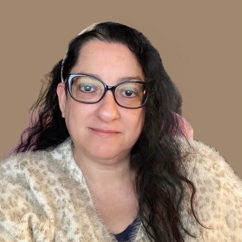 Tracie Ibrahim 6.10.25 White woman with long brown hair and glasses.